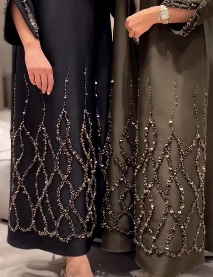 Two women in elegant black and green Diamond Net Embroidered Abayas, showcasing intricate designs and stylish silhouettes