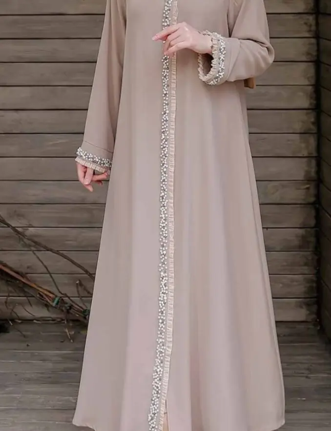 A woman wearing a beige abaya with front lace detail, showcasing elegant modest fashion