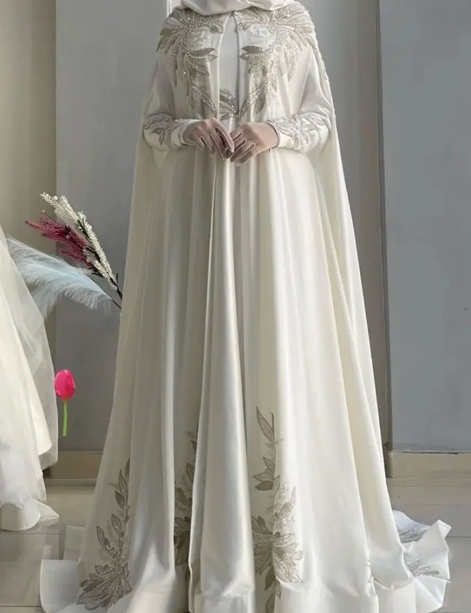 A bride in a white Muslim wedding dress, showcasing delicate embroidery and a graceful design