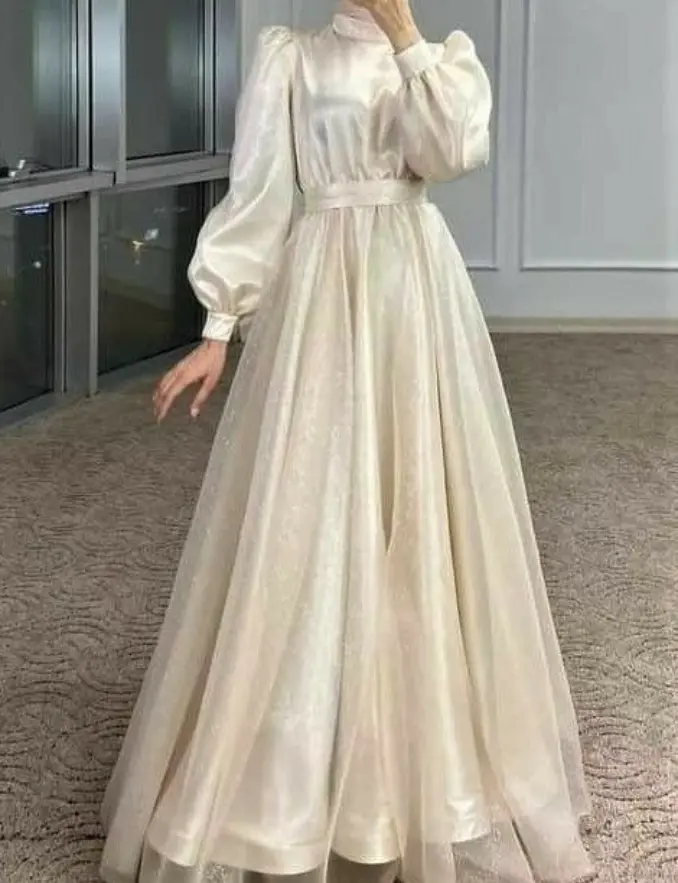 A woman poses in an Ivory Princess Puff Sleeve Gown, showcasing its elegant long white design