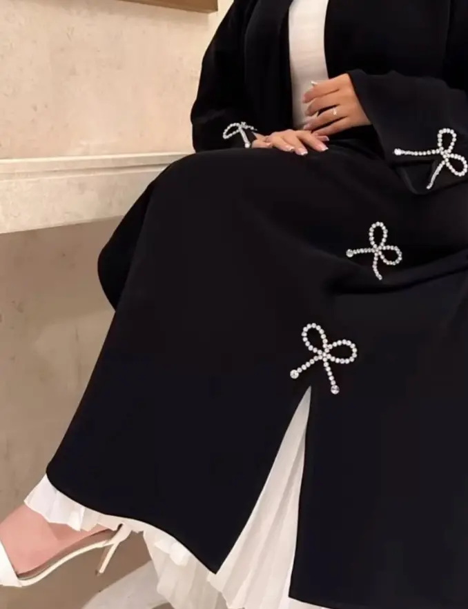 Black long sleeve abaya featuring a white bow and pearl detail, elegantly designed for modest fashion
